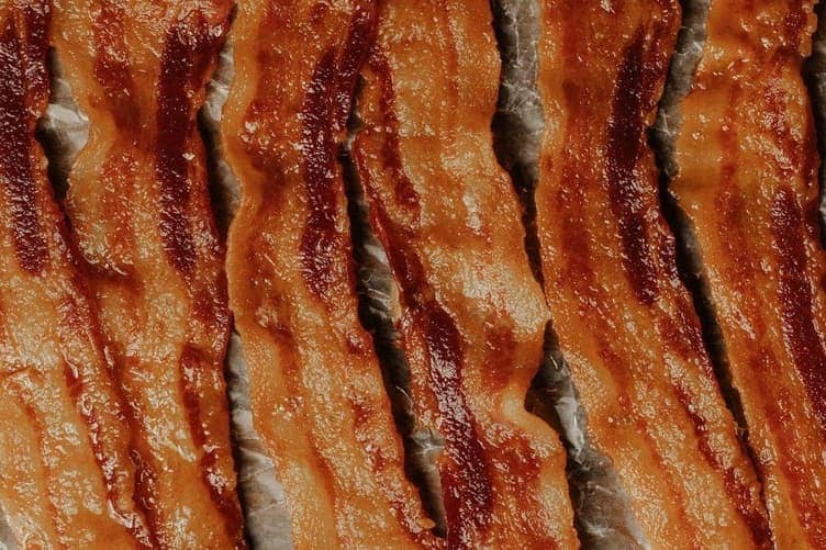 Raw bacon strips arranged on a foil-lined baking sheet
