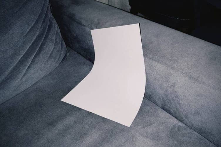 Sheet of white paper being folded in half on a flat surface